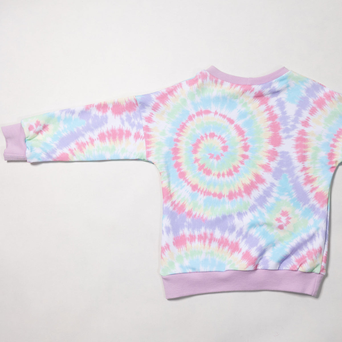 A long-sleeve crewneck sweatshirt with a pastel tie-dye spiral pattern, laid flat on a light gray background. The sweatshirt features a spiral design in pink, purple, blue, and green, with solid light purple cuffs and hem.
